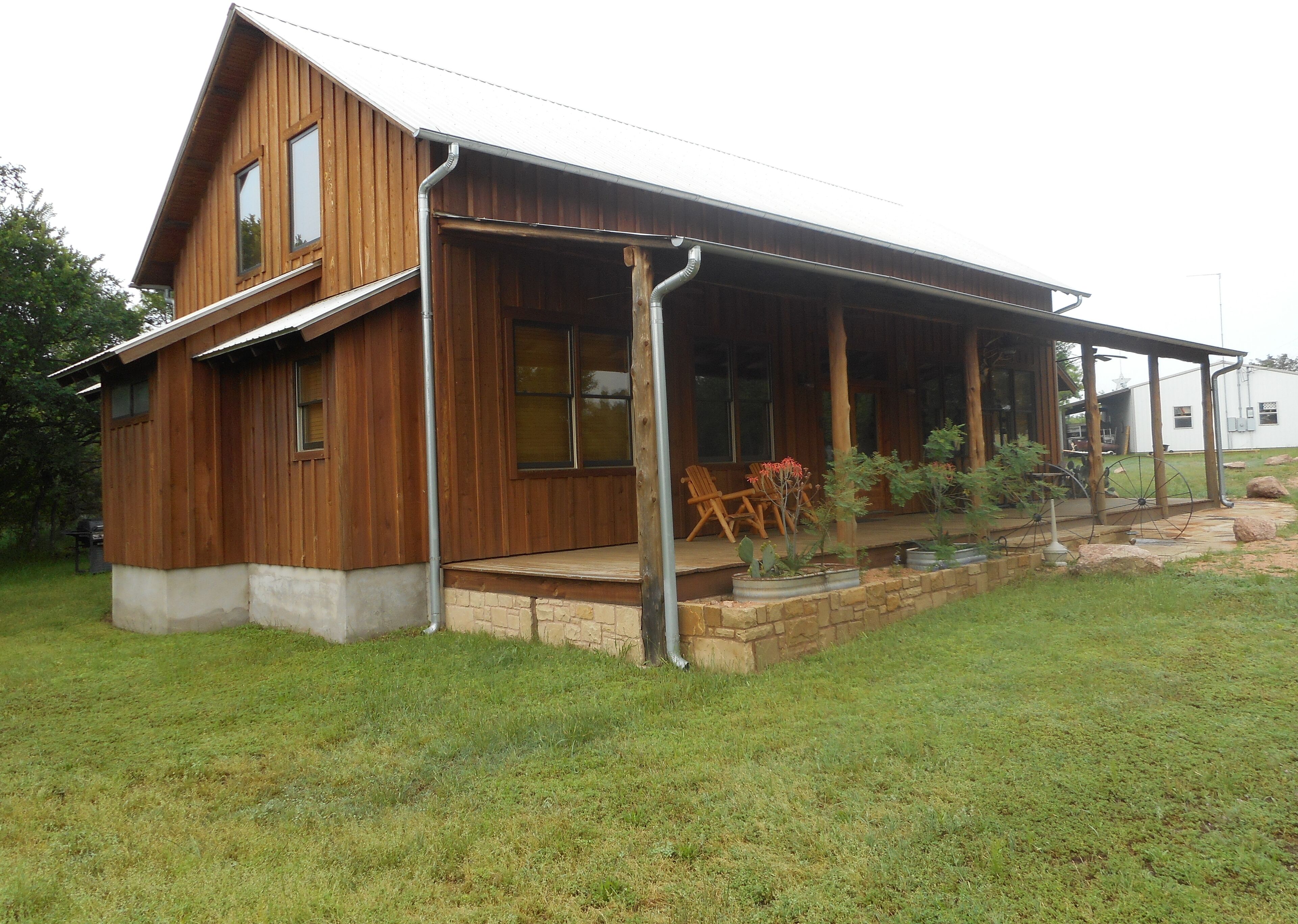A wooden cabin with a porch, large windows, and outdoor seating.