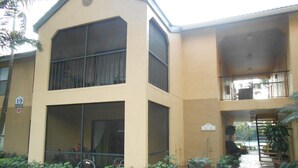 A two-story building with a flat roof and a balcony on the upper floor. - Spacious one bedroom-one bath condo (Naples)