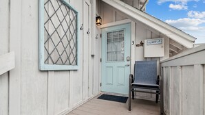 A light blue door with a window, a metal gate, and a chair outside a white building. - White beaches, walk to restaurants and shops! Family vacation /Romantic getaway! (Clearwater)
