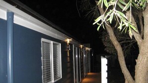 A dark blue building with a wooden deck and a tree on the right. - Ducks Bungalow- Lake Macquarie (Marks Point)