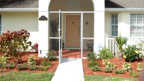 A building with a white exterior, a wooden door, and a sign indicating the address. - Private Pool + Heated Hot Tub | Lake View (Davenport)