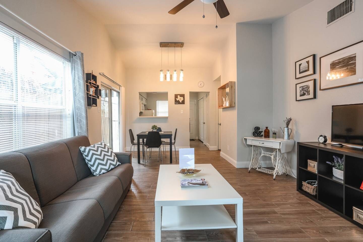 A modern living room with a sofa, coffee table, and a dining area in the background.