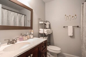 A bathroom with a sink, mirror, towel rack, and toilet.