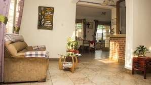 Una sala de estar con sofá, una mesa de centro de vidrio y un comedor al fondo.