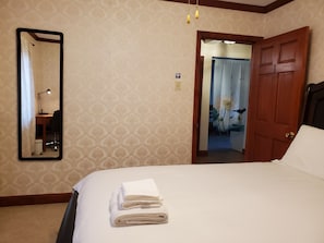 A hotel room with a bed, a desk with a lamp, a mirror, and a door leading to another room. - A beautiful 3BR Apartment near Harvard and MIT. (Cambridge)