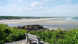 A bench overlooking a beach with a rocky outcrop in the foreground.