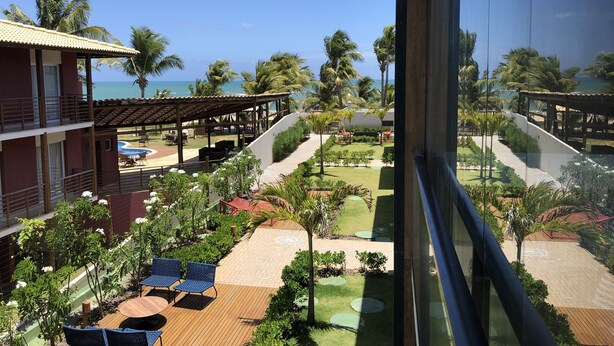 A resort with a pool, outdoor seating, and a view of the ocean. - Beachfront village with natural pools near the condominium! (Camaçari)