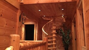A wooden interior with a spiral staircase leading to a balcony.