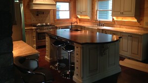 A spacious kitchen with a large island, white cabinetry, and a modern chandelier.