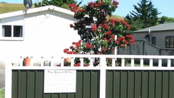 Une propriété clôturée, avec une pancarte indiquant « The Beach Villas » et une antenne parabolique sur le toit.