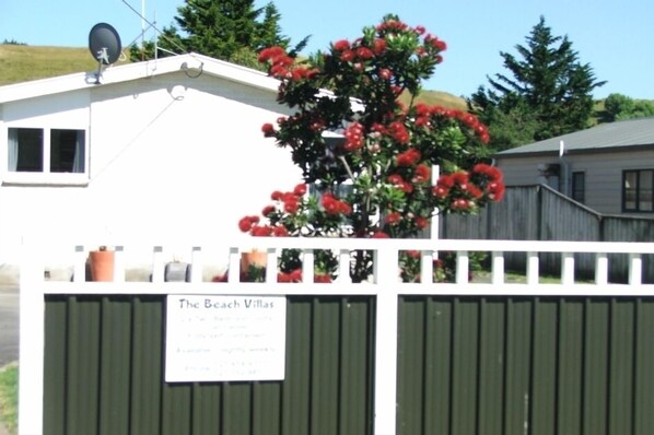 A fenced property with a sign reading 'The Beach Villas' and a satellite dish on the roof.