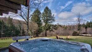 Ein Whirlpool in einem Garten mit einer Holzterrasse, umgeben von Bäumen und einer Rasenfläche.