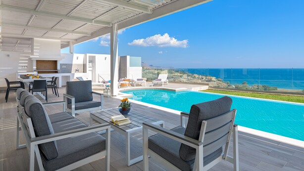 A modern outdoor living area with a pool, seating, and a view of the sea. - Villa Gaia (Rhodes)