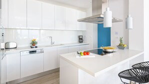 A modern kitchen with white cabinetry, a central island with a cutting board, and a coffee maker. - Villa Gaia (Rhodes)