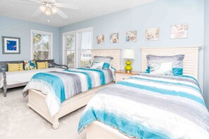 A bedroom with two beds, a ceiling fan, and a window with blinds. - Feels Like Home-3 BR Oceanfront Duplex; Covered Porches (Topsail Beach)