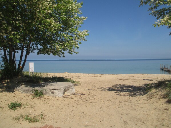 Ein Strand mit einem Schild, das einen Privatstrand kennzeichnet, strahlend blauem Himmel und ruhiger See.