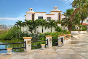 Stunning villa with a Mediterranean facade, surrounded by lush greenery and a paved pathway leading to the entrance.