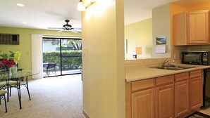 A kitchen with wooden cabinets, a microwave, and a glass dining table with chairs.