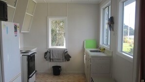 Una cocina pequeña con estufa, lavamanos y ventana.