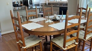 A dining area with a round wooden table surrounded by wooden chairs with cushioned seats. - Oceanfront Home on Folly Beach, SC (Folly Beach)