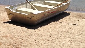 A small wooden boat with a paddle, labeled "PrinceCraft," on a sandy shore by a calm lake with a forested hill in the background. - Relax at Crescent Lake (wolfeboro)