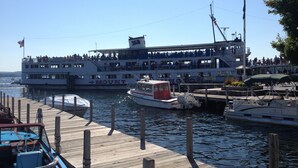 A large ferry docked at a pier with a multi-level structure and a smaller boat nearby. - Relax at Crescent Lake (wolfeboro)