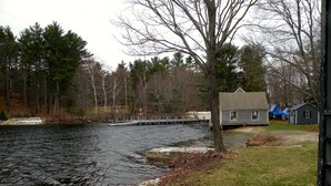 A riverside property with a dock, a small house, and a grassy area. - Relax at Crescent Lake (wolfeboro)
