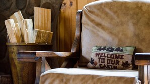 Ein rustikales Cabin-Interieur mit einem Holzstuhl und einem Kissen mit freundlicher Begrüßungstafel.