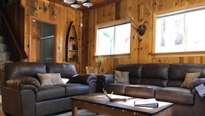 Ein gemütliches Wohnzimmer mit zwei Ledersofas, einem Holztisch und einem großen Fenster.