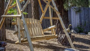 Ein Holzschaukelstuhl mit Bank, umgeben von Bäumen und einem Holzzaun.