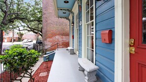 Un edificio azul con puerta roja, un buzón y un banco en el exterior.
