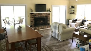 Una sala de estar con chimenea, televisor, zona de comedor y sofá.