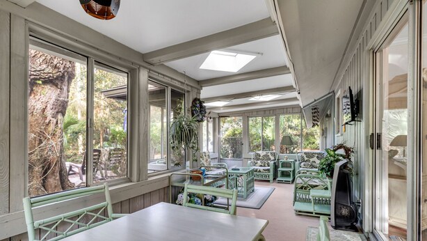 Una sala de estar con ventanales, una mesa grande y sillas, y vistas al exterior.