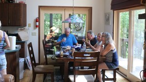 A dining area with a table, chairs, and a hanging light fixture.