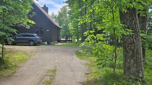A gravel driveway leading to a cabin with a car parked nearby.