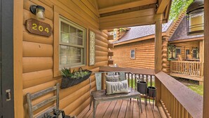 Une cabane en bois avec un porche, une plaque numérotée « 204 », un banc, une table et une lanterne.