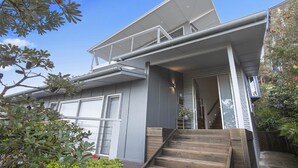 A modern house with a covered porch, a staircase leading to the entrance, and a view of the surrounding greenery. - the nest at killcare (Killcare)