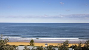 A beach with a clear view of the ocean, a sandy shore, and some vegetation. - the nest at killcare (Killcare)