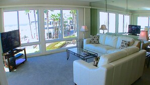 Un salón amplio con un sofá blanco grande, una mesa de centro y un televisor sobre un mueble.