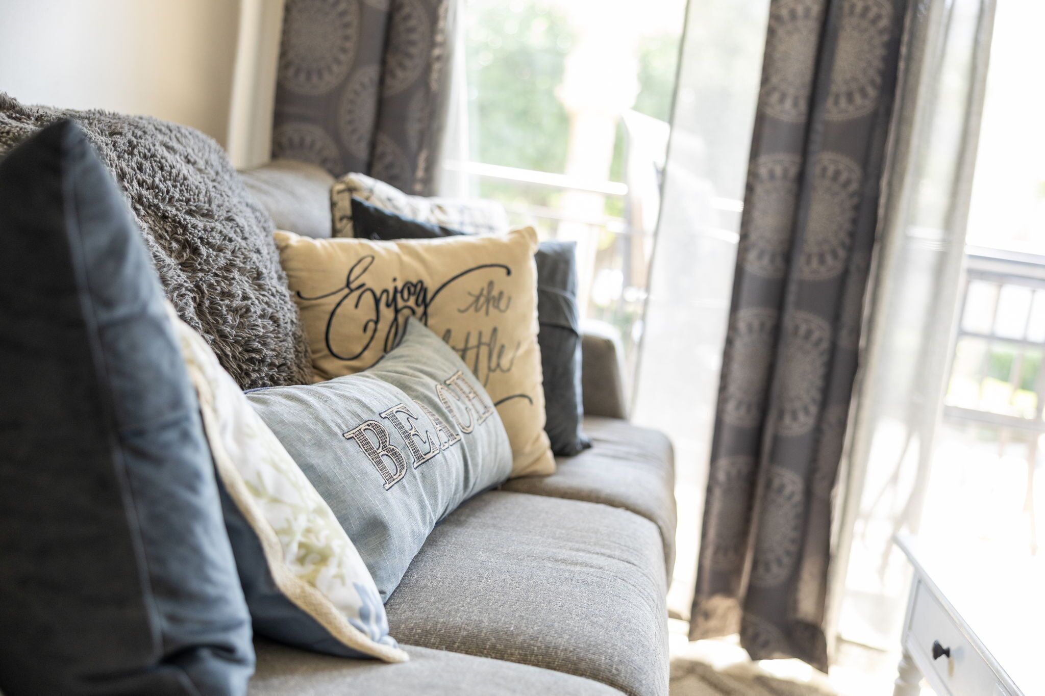 A sofa with multiple pillows, including one with the text "Enjoy the little things."