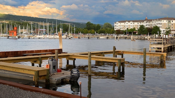 Ein Yachthafen mit Holkaianlagen, Booten und einem Gebäude mit vielen Fenstern im Hintergrund.