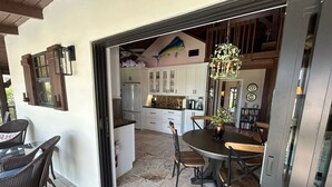 Cocina integrada con armarios blancos, comedor con mesa y sillas redondas, y vista hacia la zona de estar contigua.