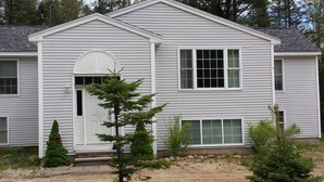 A two-story house with a symmetrical facade, a central entrance with a fanlight, and a small porch. - Spacious vacation house with game room close to North Conway and outlets. (Madison)