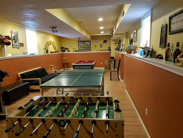 Una habitación con mesa de fútbol, mesa de billar y un sofá.