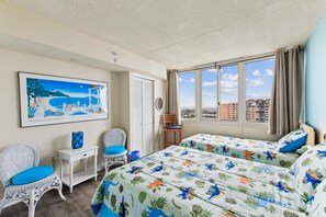 Habitación de hotel con una cama, dos sillas, una mesita, un cuadro y una ventana con vistas a la ciudad.
