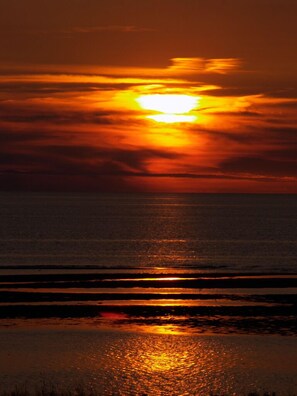 A sunset over the ocean with a calm sea reflecting the sky.