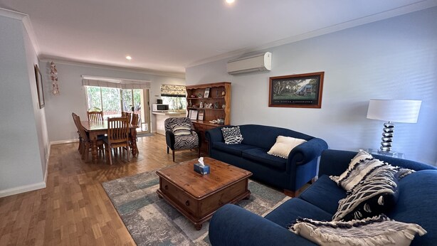 A living room with a blue sofa, wooden coffee table, and a dining area with a wooden table and chairs.