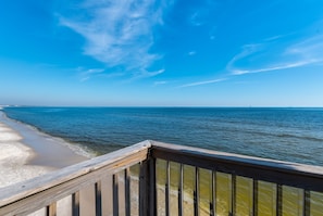 A wooden deck overlooking a beach with clear skies. - Beachfront Bliss with Spacious Comfort & Direct Access - Sand Bottoms (Dauphin Island)