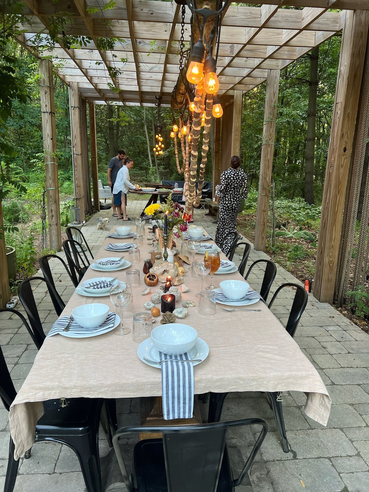 Un espace de restauration en plein air avec une longue table dressée pour accueillir plusieurs convives, entourée de chaises.