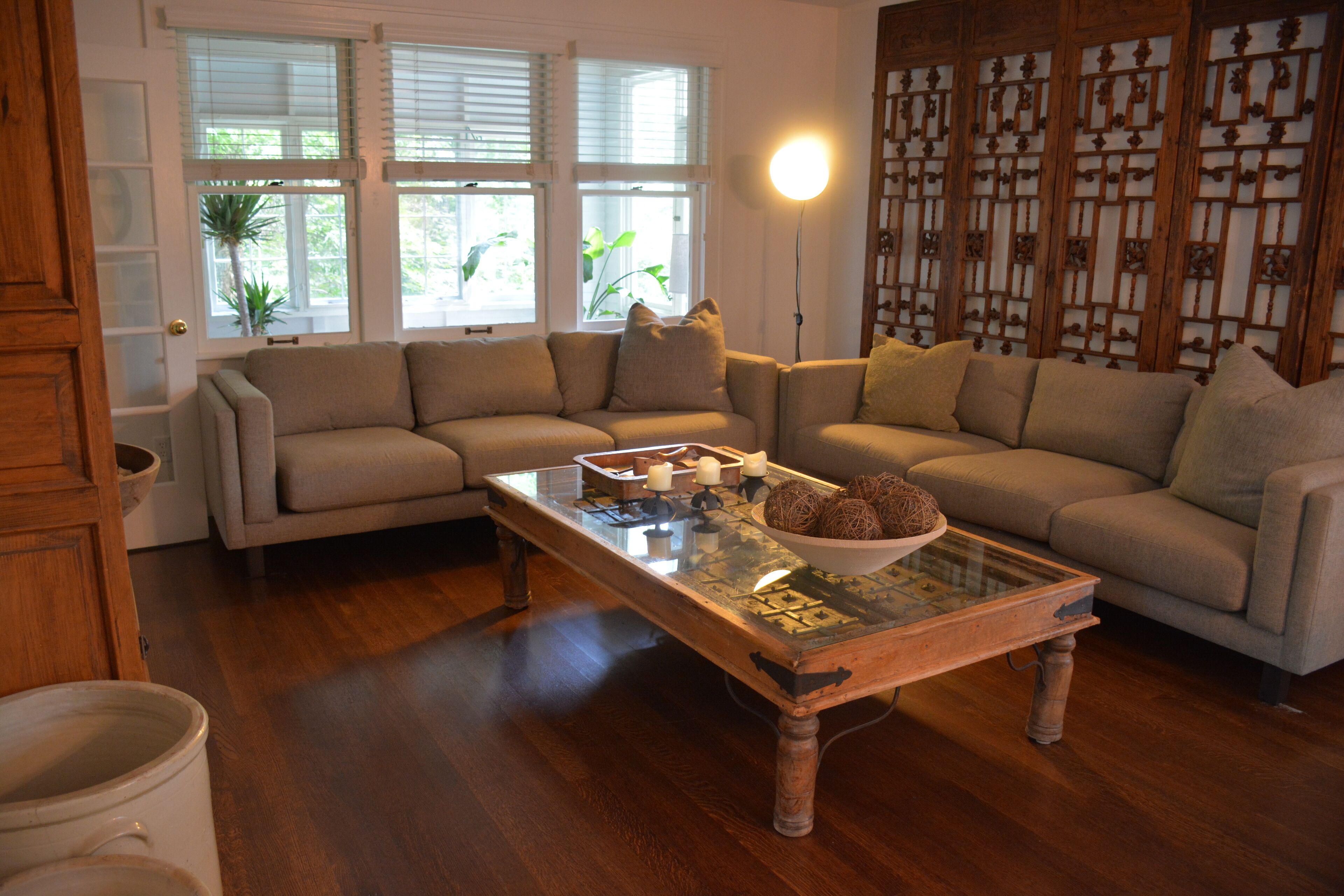 A living room with a glass coffee table, two sofas, and a wooden floor.